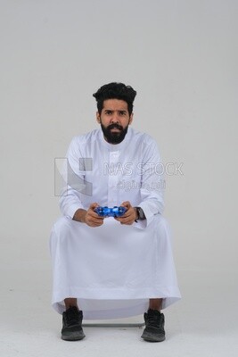 saudi  man holding a joystick in his hand and playing video games, with gestures and expressions that indicate focus and harmony, fun and entertainment with video games