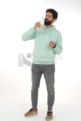 Saudi man wearing casual clothes, drinking from a water bottle, Saudi model, white background