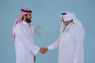 Two Saudi  businessmen shaking hands in traditional Saudi dress gesturing with handshake gesture, welcome, agreement, peace, acquaintance, dating concept