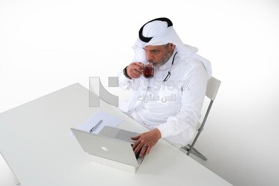 top view of an elderly Saudi man sitting in front of a laptop, business feasibility study, Saudi model