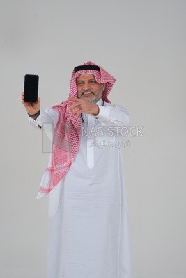 Saudi man using a mobile phone pointing on it, communicating with individuals, online requests and marketing, social relations, using technical devices, white background