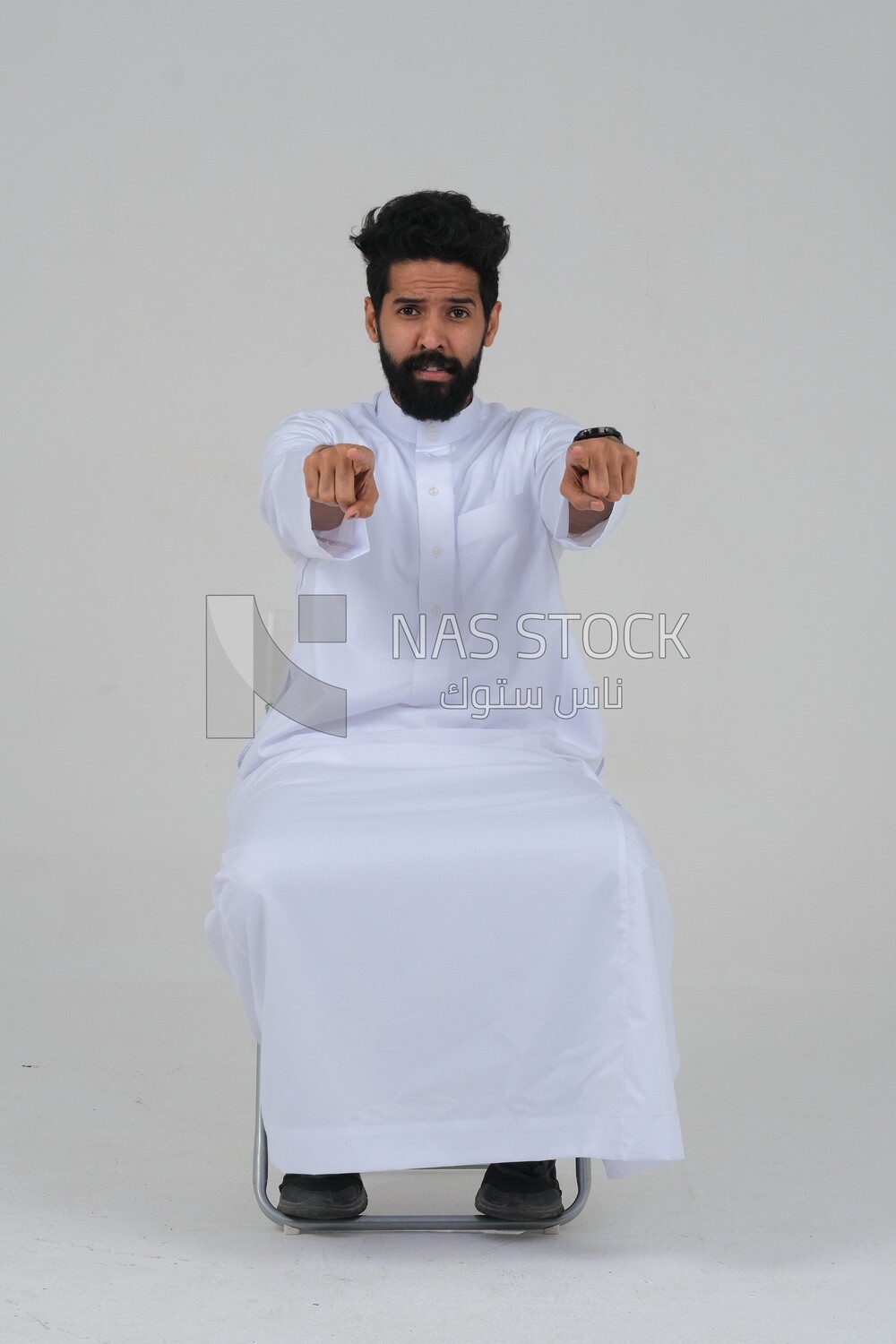 close-up of a Saudi man in traditional Saudi dress, sitting on a chair pointing , Saudi model, white background