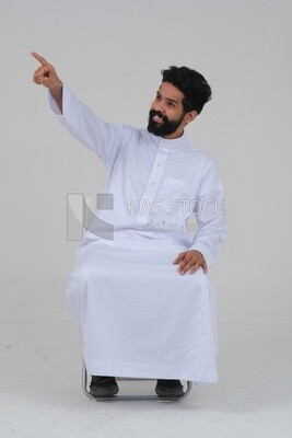 صورة مقربة لرجل سعودي يرتدي الزي السعودي التقليدي يشير بعيدا، منظر جانبى ، موديل سعودى ، خلفية بيضاء
