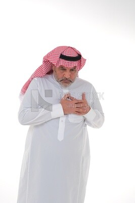 saudi man putting his hand on his chest and feeling a state of tingling and pain in his heart, close-up, a young Saudi man wearing a white dress with a shemagh and headband, white background