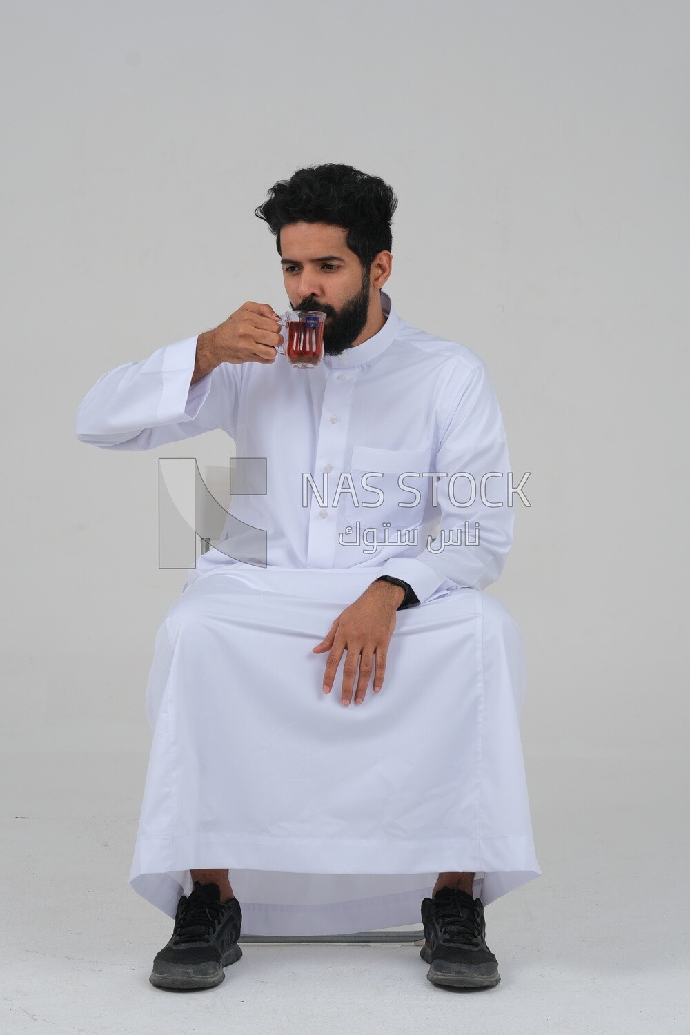 Saudi man wearing a white dress, drinking a cup of tea, self-confidence, white background, Saudi model