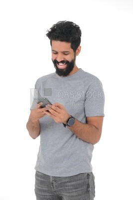 close-up of a Saudi man, wearing casual clothes, carrying his mobile phone, Saudi model, white background