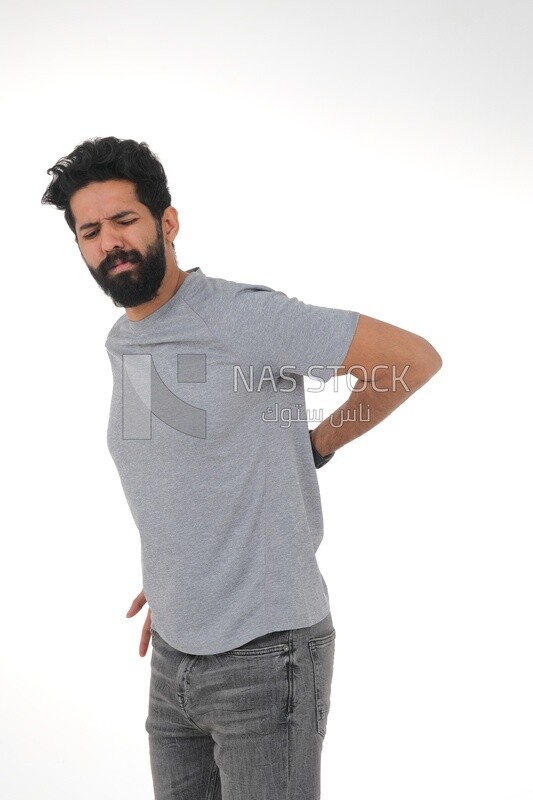 Saudi man wearing a casual dress with his hands on his back, feeling