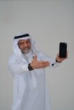 Saudi man using a mobile phone pointing on it, communicating with individuals, online requests and marketing, social relations, using technical devices, white background