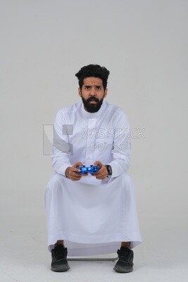 saudi man holding a joystick in his hand and playing video games, with gestures and expressions that indicate focus and harmony, fun and entertainment with video games, PlayStation entertainment ga