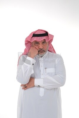 saudi man wearing a traditional Saudi dress, putting his hand on his face with gestures and facial expressions and hands indicating boredom, reflecting on a problem solution, thinking about a topic, f