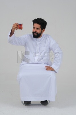 Saudi man wearing a white dress, drinking a cup of tea, self-confidence, white background, Saudi model