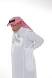 Saudi man wearing a casual dress, man putting his hands on his back, gestures indicating back and spine pain, fatigue and exhaustion, muscle spasms, health problems