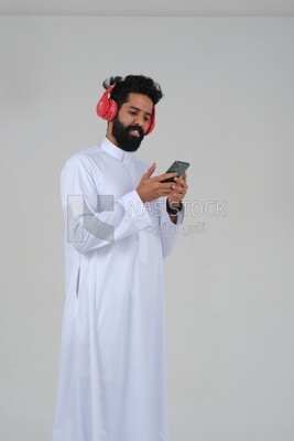 Saudi man puts on a headset and enjoys listening to songs and music, recording songs and audios, voiceover, presenting radio programs, talent and art, white background, Saudi model