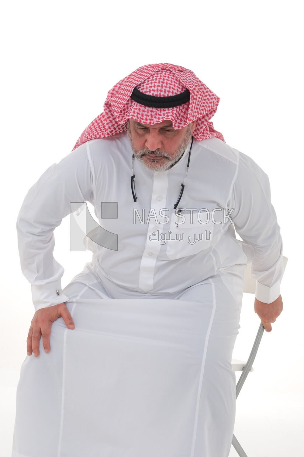 elderly Saudi man trying to sit on a chair, back and spine pain, fatigue and exhaustion, muscle spasms, health problems, white background, Saudi model