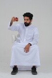 Saudi man wearing a white dress, drinking a cup of tea, self-confidence, white background, Saudi model