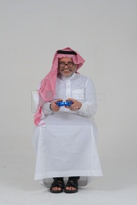 saudi  man holding a joystick in his hand and playing video games, with gestures and expressions that indicate focus and harmony, fun and entertainment with video games