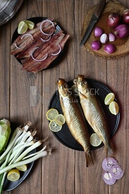 Smoked herring on a Cutting and Serving Board, herring fillet with lemon on a plate, lemon and onion, traditional food, smoked fish