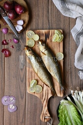 Smoked herring on a Cutting and Serving Board, lemon and onion, traditional food, smoked fish