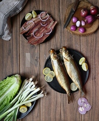 Smoked herring on a Cutting and Serving Board, herring fillet with lemon on a plate, lemon and onion, traditional food, smoked fish