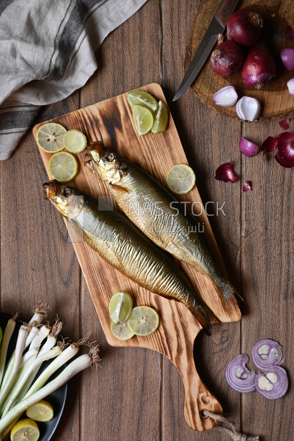 Smoked herring on a Cutting and Serving Board, lemon and onion, traditional food, smoked fish