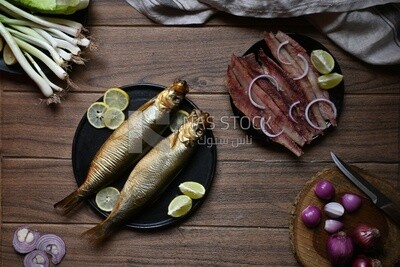 Smoked herring on a Cutting and Serving Board, herring fillet with lemon on a plate, lemon and onion, traditional food, smoked fish