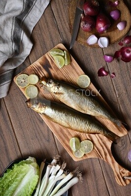 Smoked herring on a Cutting and Serving Board, lemon and onion, traditional food, smoked fish
