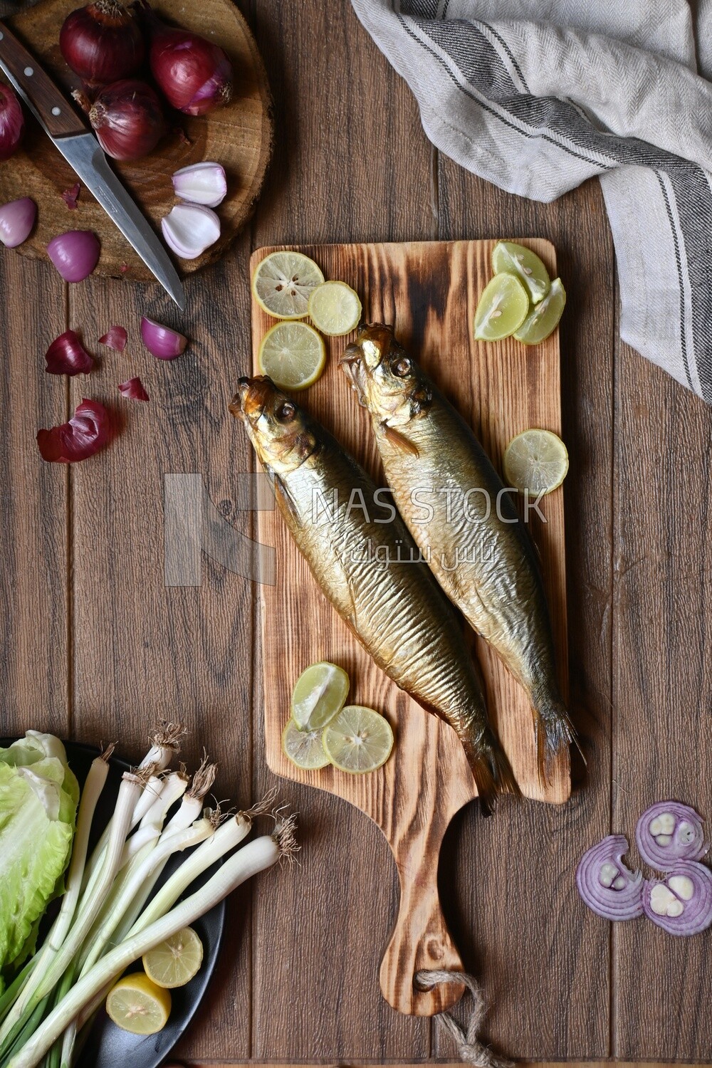 Smoked herring on a Cutting and Serving Board, lemon and onion, traditional food, smoked fish