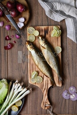 Smoked herring on a Cutting and Serving Board, lemon and onion, traditional food, smoked fish