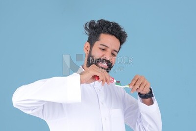 Saudi man holding a toothbrush, brushing his teeth with toothpaste, skincare and hygiene, self-care, Saudi model, white background