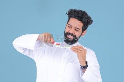 Saudi man holding a toothbrush, brushing his teeth with toothpaste, skincare and hygiene, self-care, Saudi model, white background