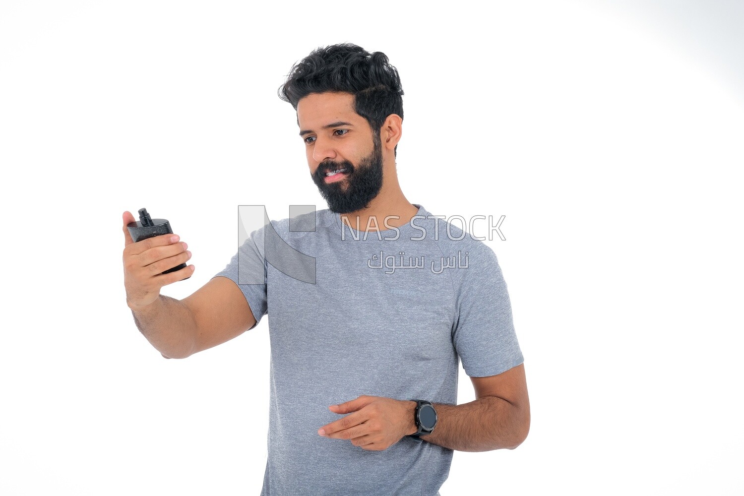 Saudi man holding a perfume bottle, applying perfume, selfcare, skin care and hygiene, Saudi model, white background