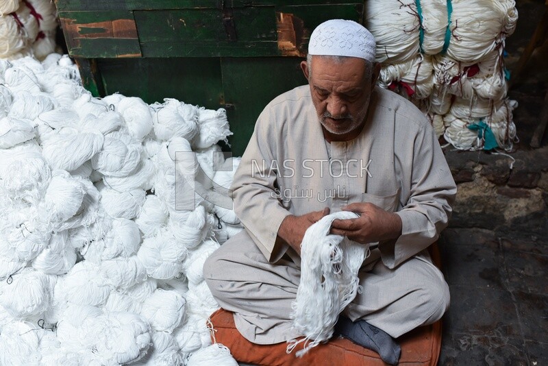 A man collects balls of white thread