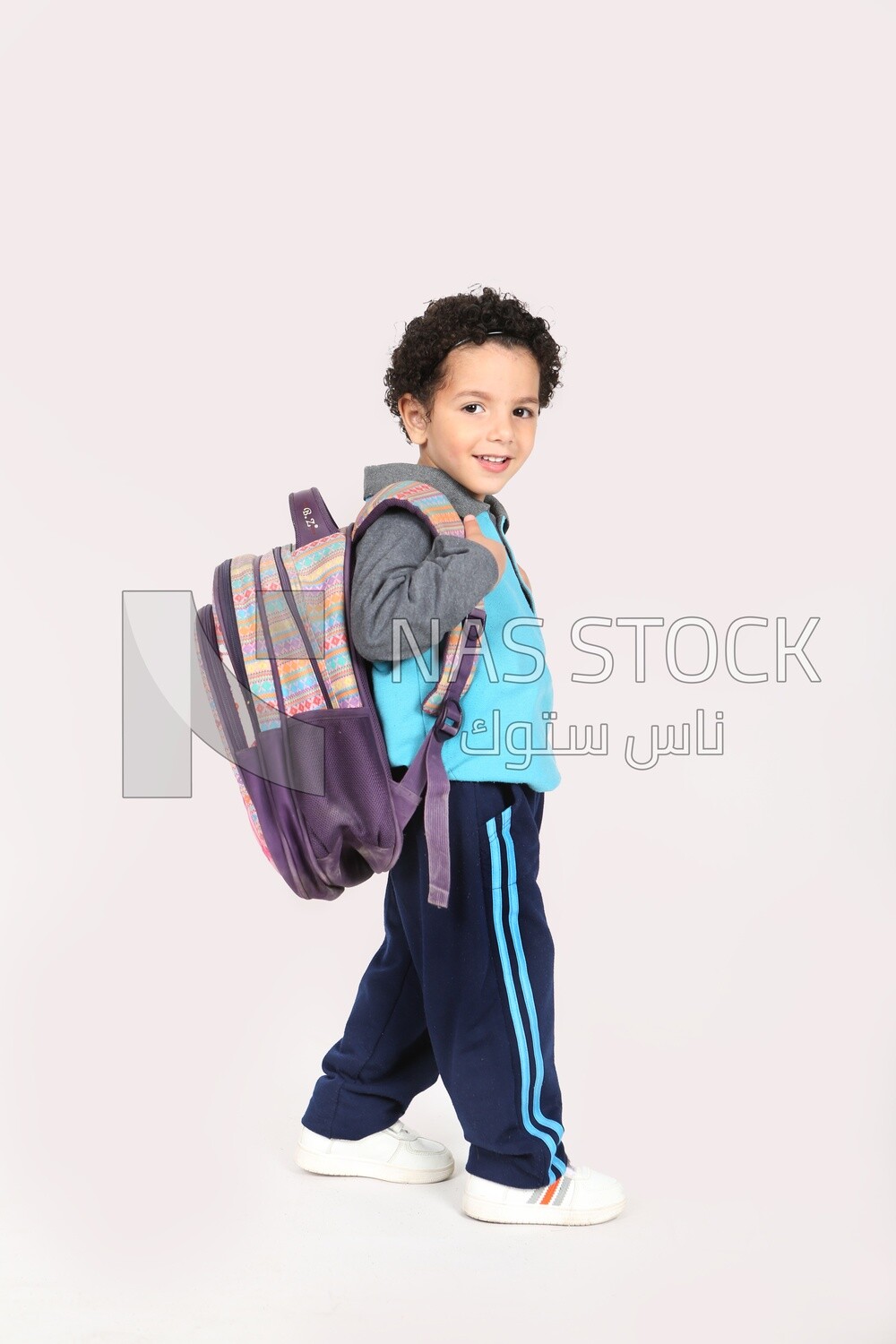 A boy wearing his bag on a white background