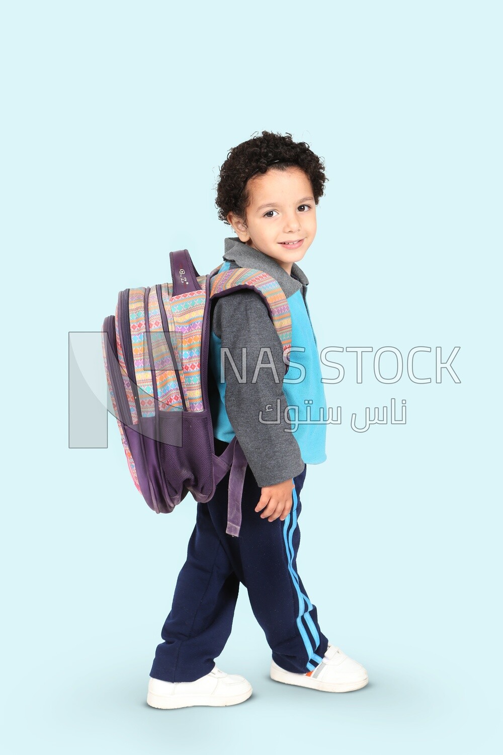 A boy wearing his bag on a blue background