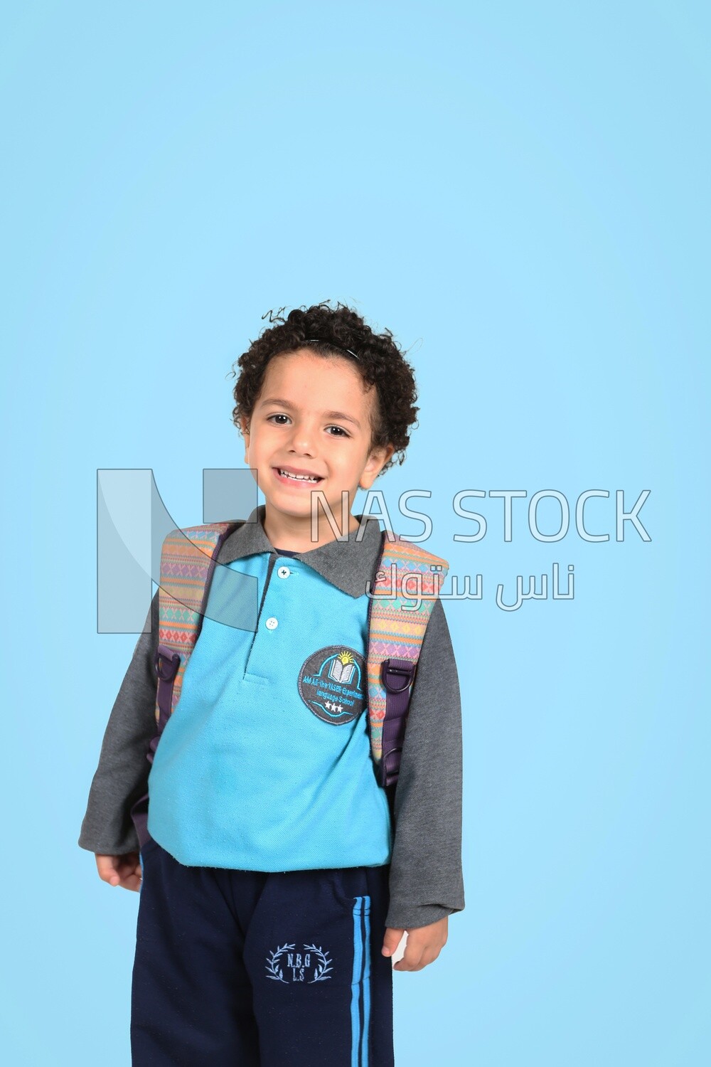 A boy wearing his bag on a blue background