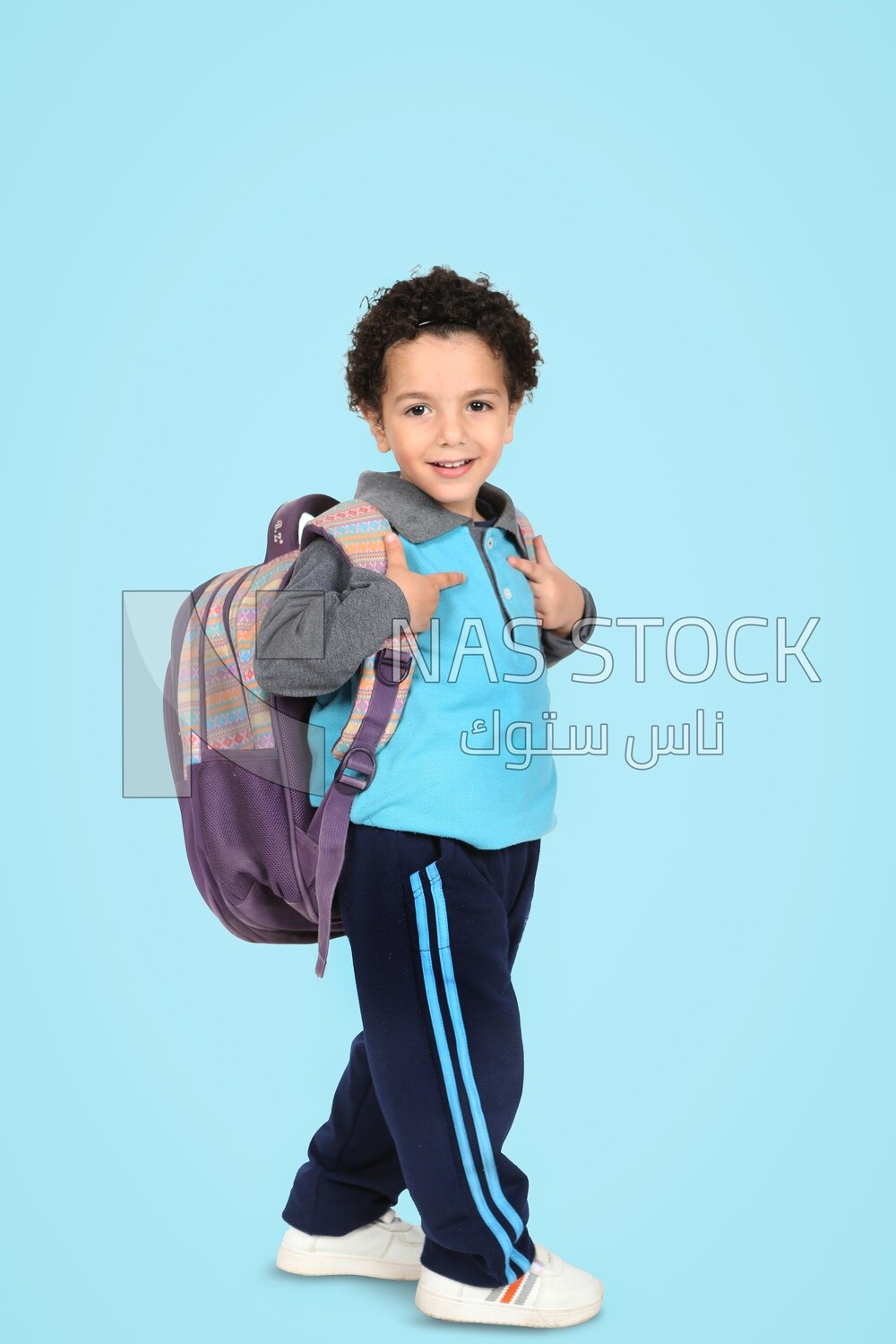 A boy wearing his bag on a blue background