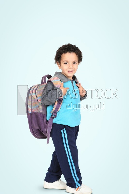 A boy wearing his bag on a blue background