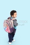 A boy wearing his bag on a blue background