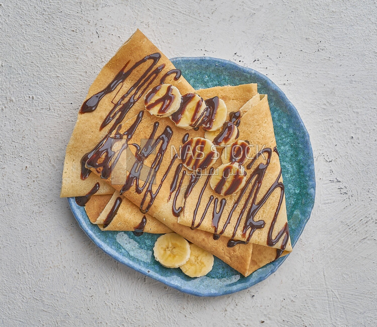 Chocolate crepe with banana slices on a solid background