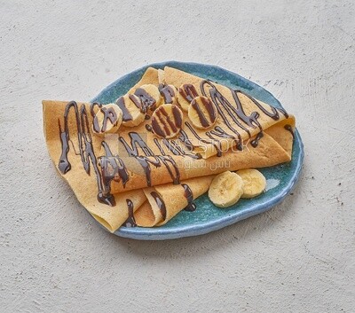Chocolate crepe with banana slices on a solid background