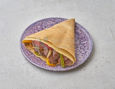 Sausage crepe with vegetables on a solid background