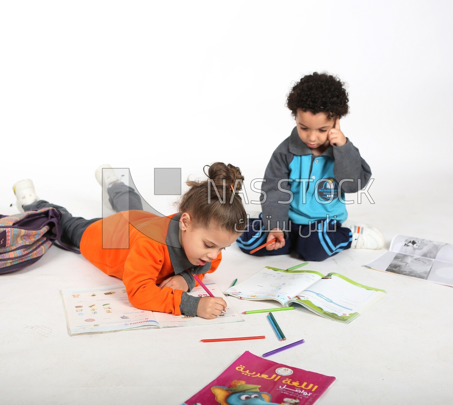 A brother and a sister sitting on the floor studying