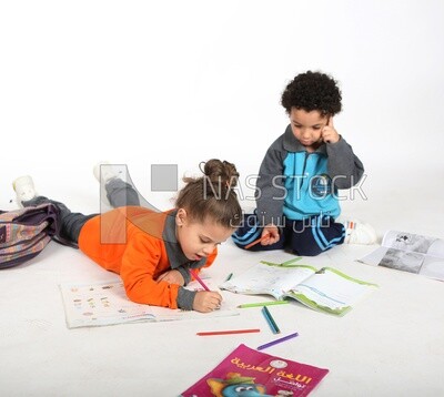 A brother and a sister sitting on the floor studying