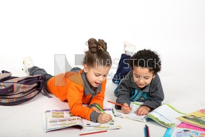 A brother and a sister sitting on the floor studying