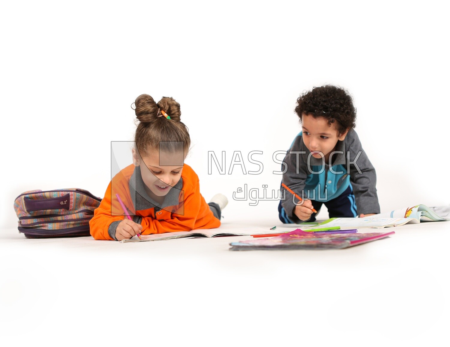 A brother and a sister sitting on the floor studying