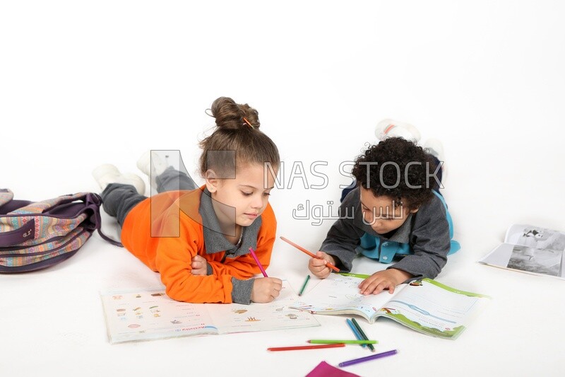 A brother and a sister sitting on the floor studying