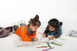 A brother and a sister sitting on the floor studying