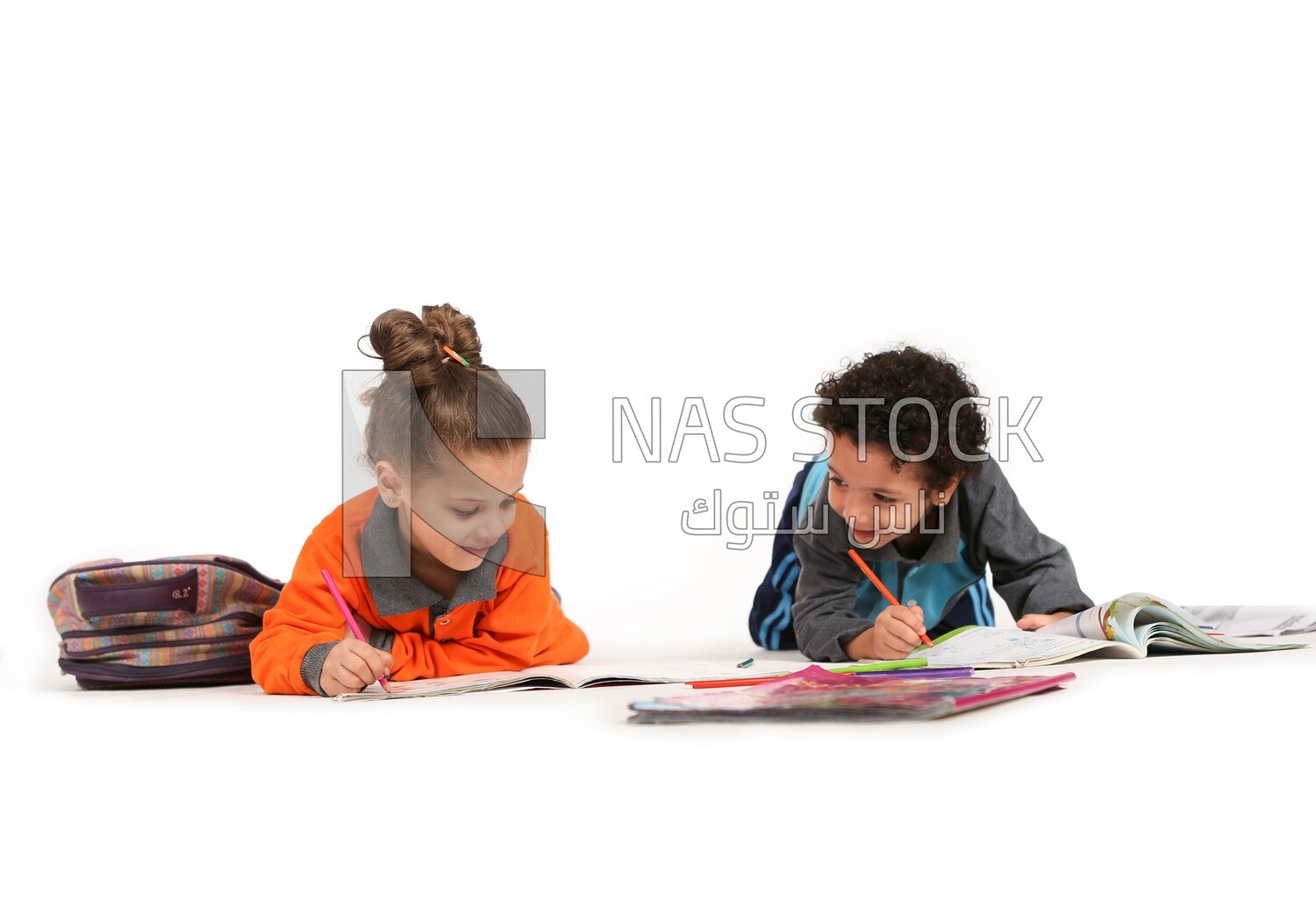 A brother and a sister sitting on the floor studying