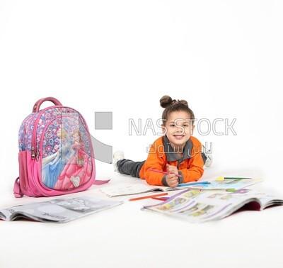 A schoolgirl sitting on the floor and studying