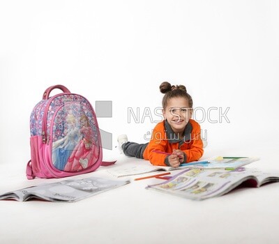 A schoolgirl sitting on the floor and studying